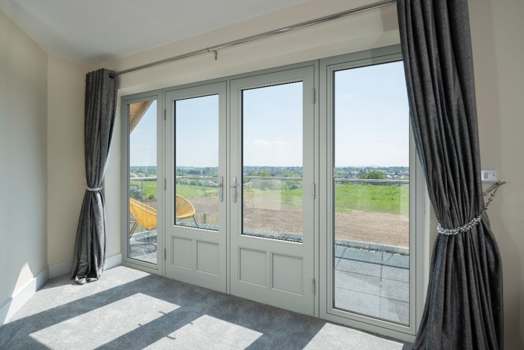 Interior view of cream Residence French doors opening onto a balcony with countryside views.