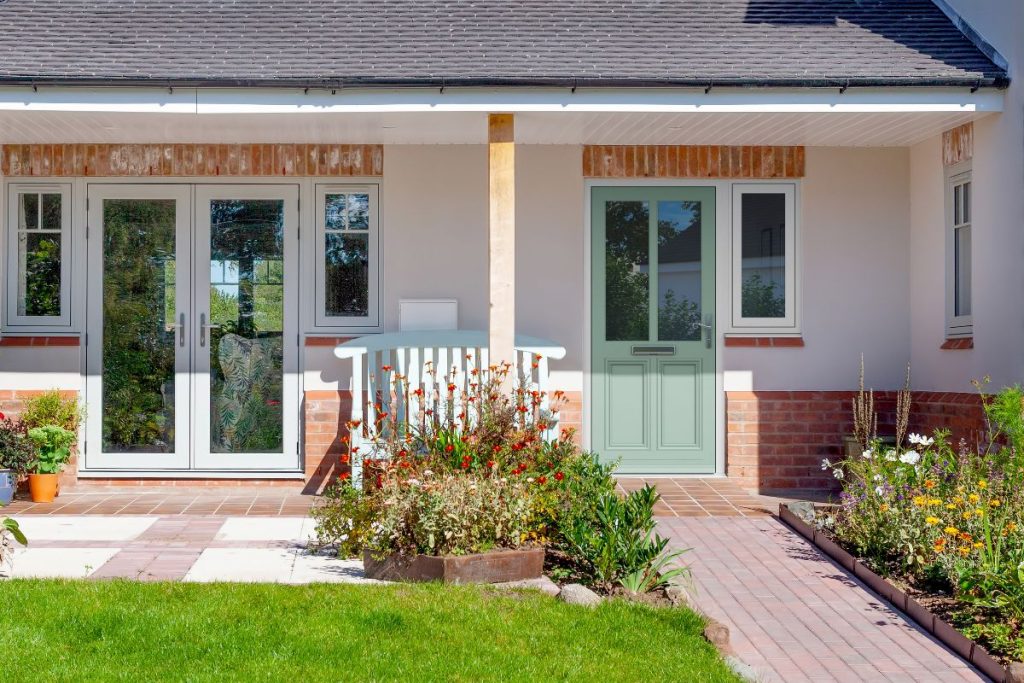 Modern home with a pastel green Residence entrance door and matching grey Residence French doors, opening onto a garden patio.