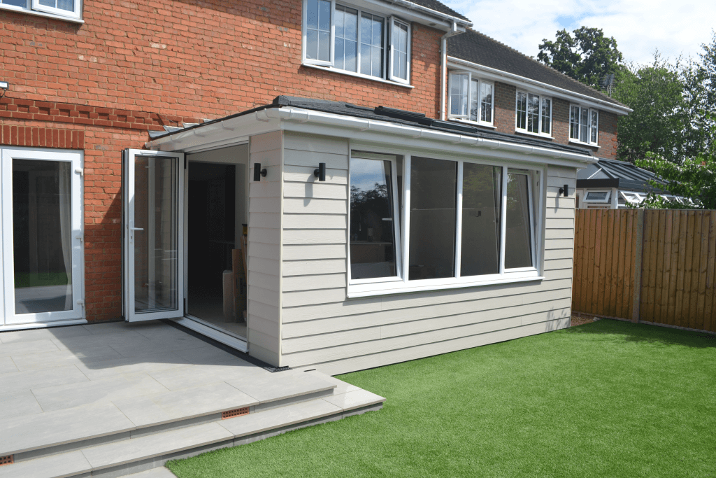 An icoextension with large glazed windows amidst a modern garden with a patio