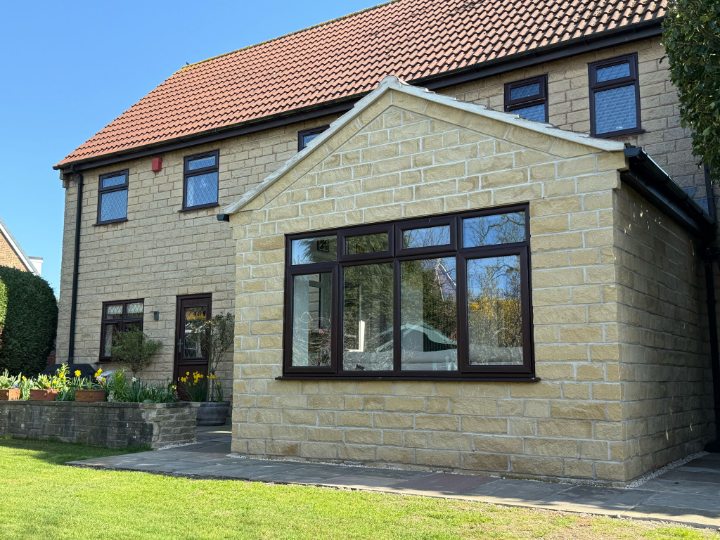 Discover a charming suburban house featuring a modern brick extension, terracotta roof, and a vibrant spring garden with daffodils under a clear blue sky. Ideal for home design and real estate.